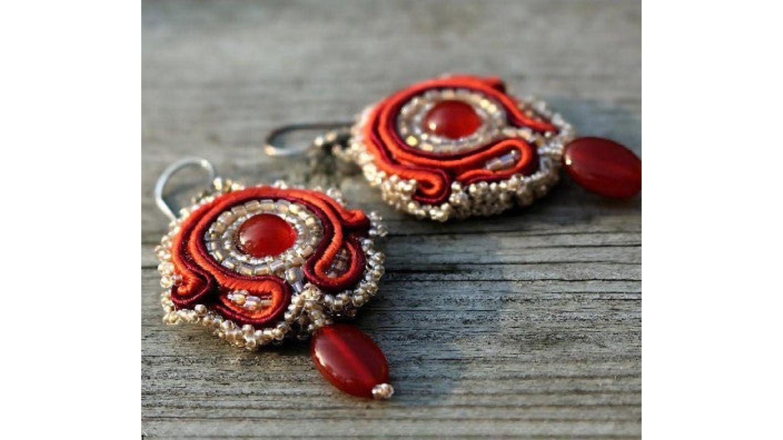 Oranssit tekstiilikorut soutache-nauhalla ja karneolikivillä.